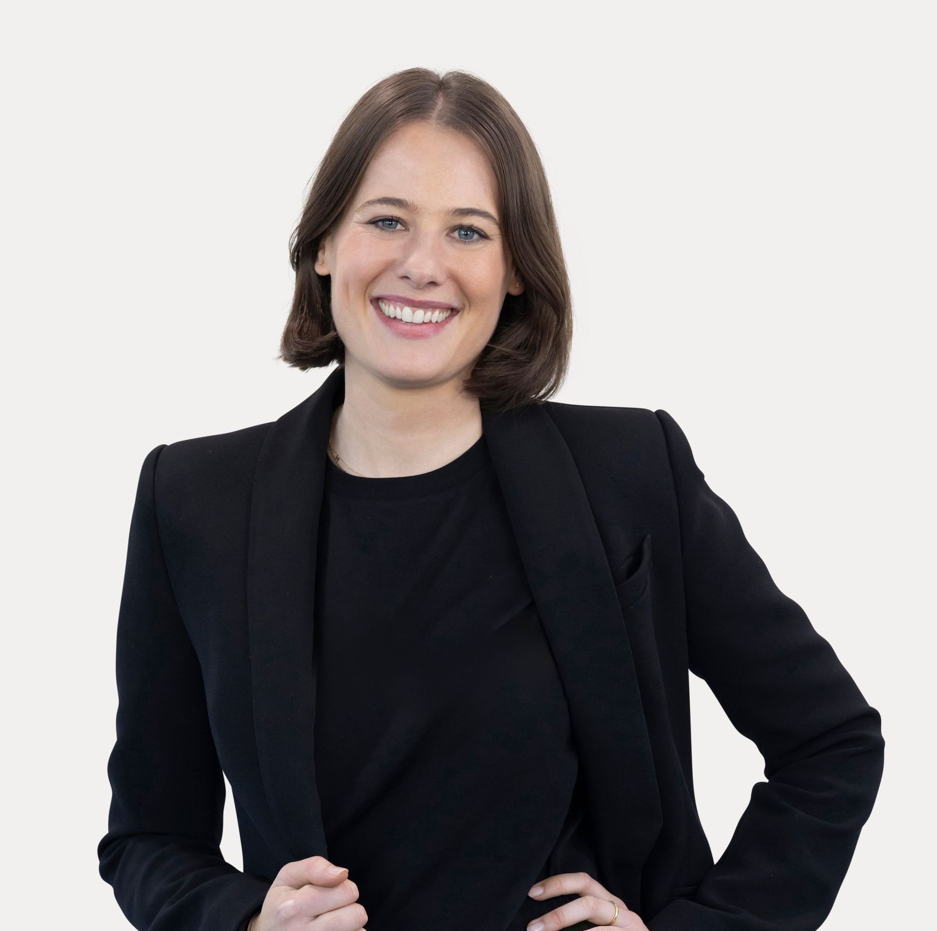 A woman in a black jacket is smiling with her arms crossed.