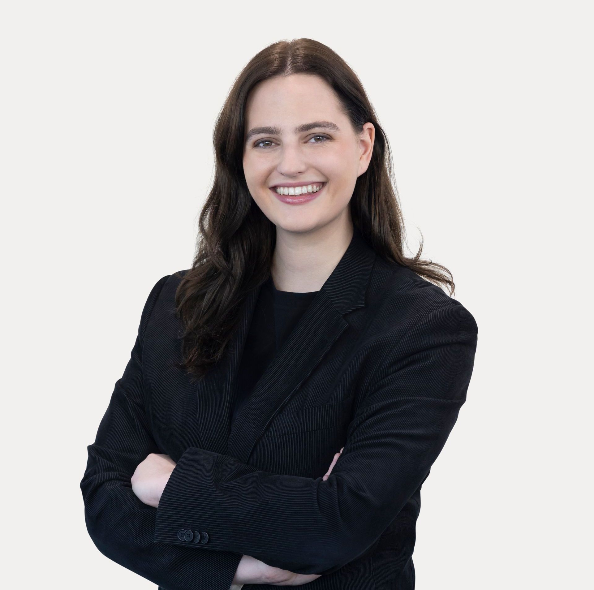 A woman wearing glasses and a black jacket is smiling.