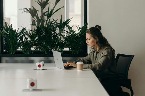 A woman is sitting at a table using a laptop computer.