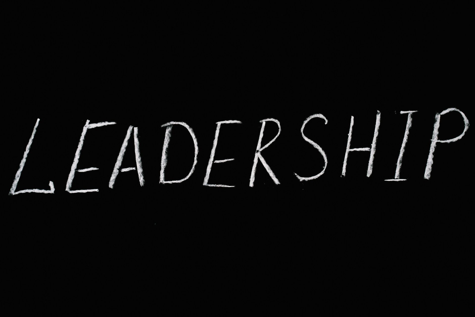 The word leadership is written in white chalk on a black background
