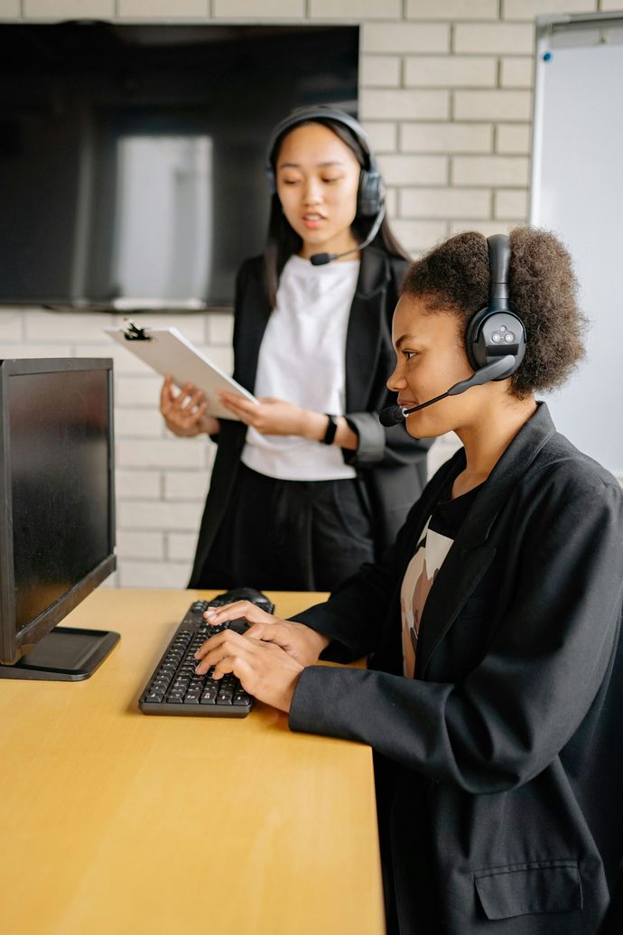 A woman wearing a headset is sitting at a desk using a computer.