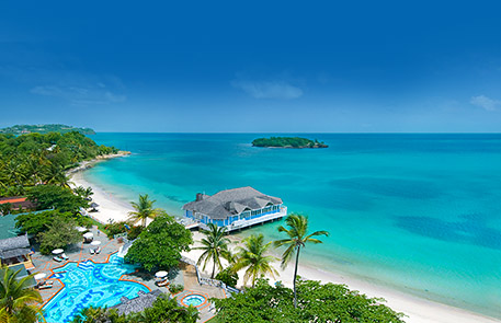 Tropical beach resort with blue ocean, white sand, and a floating restaurant.