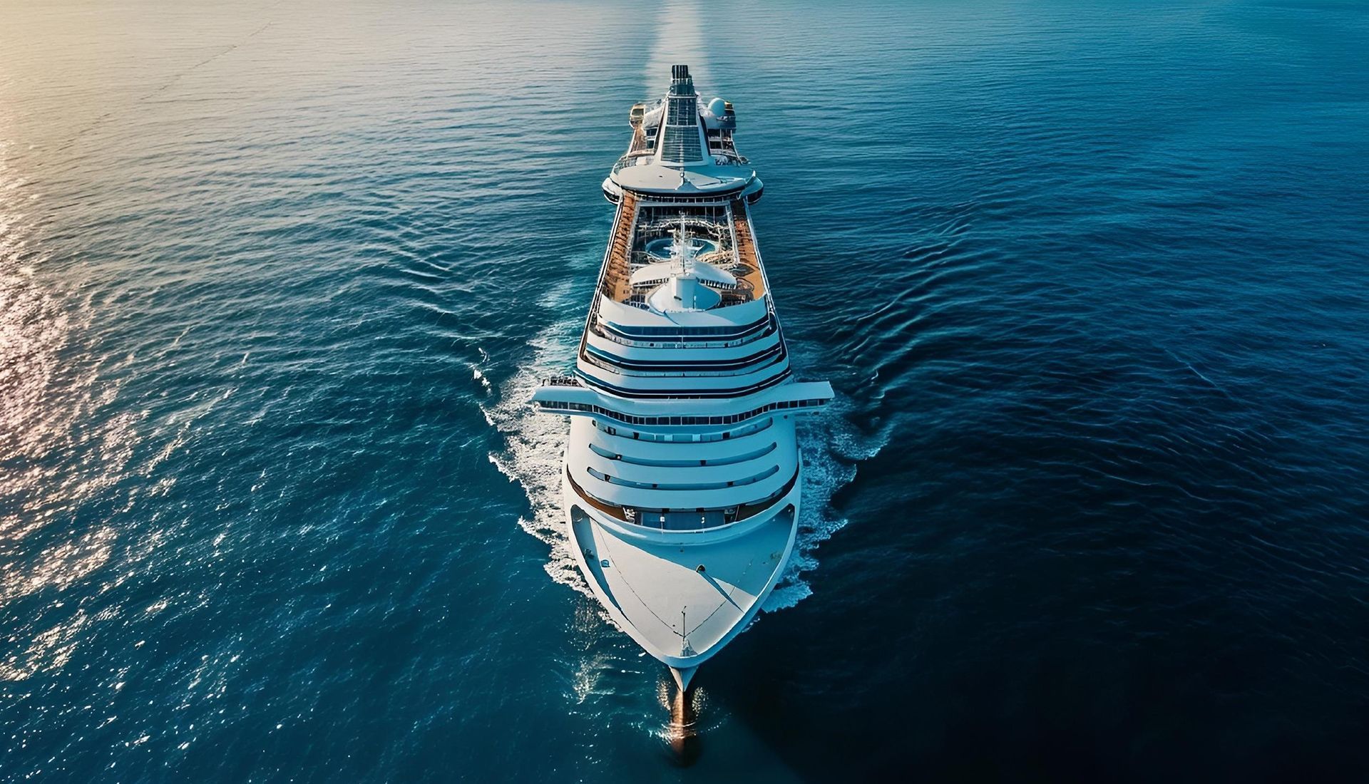 Cruise ship sailing on a blue ocean, leaving a white wake.