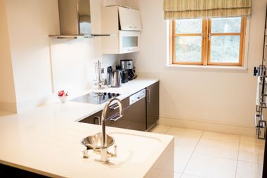 Modern kitchen with white countertops, stainless steel appliances, and a window.