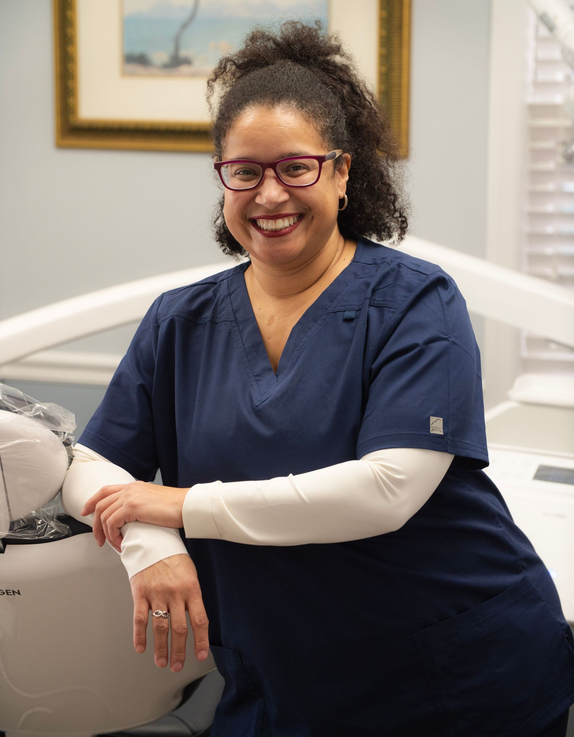 A woman wearing glasses and a red shirt is smiling for the camera.