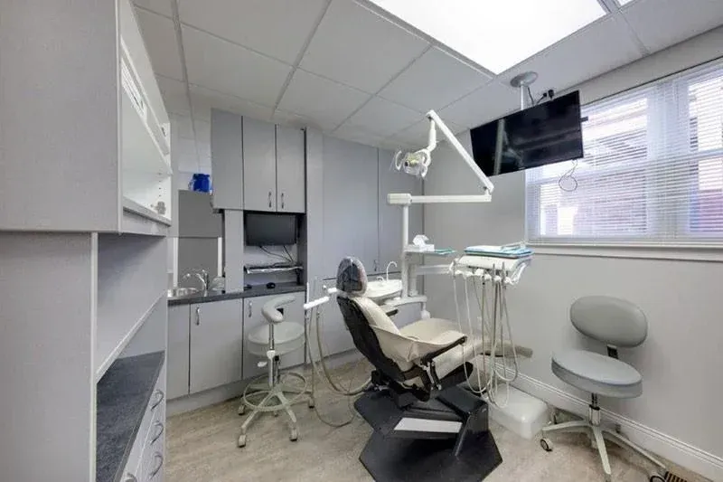 A dental office with a dental chair and a television on the ceiling.