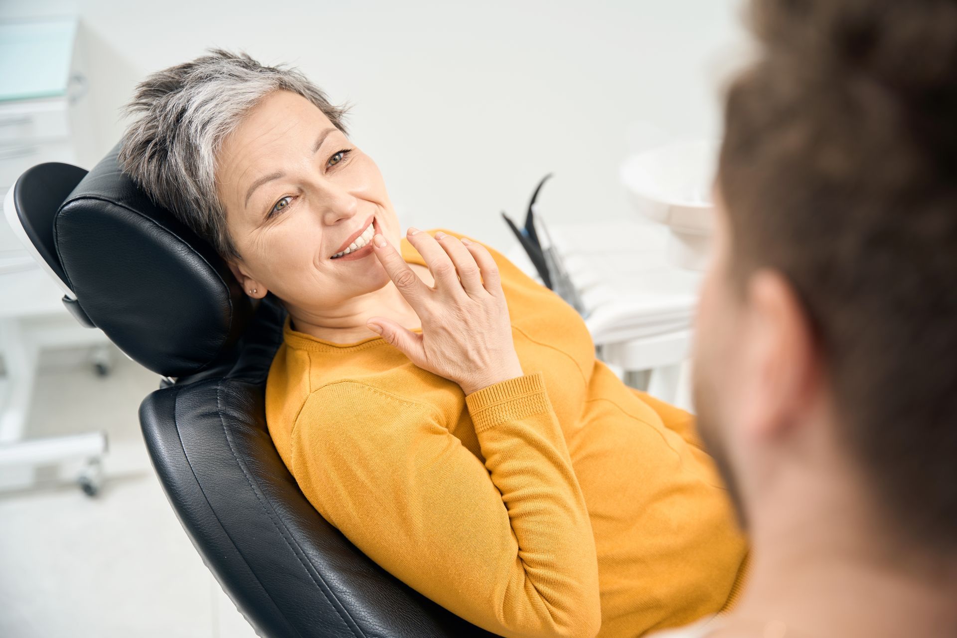 A woman is sitting in a dental chair talking to a dentist.