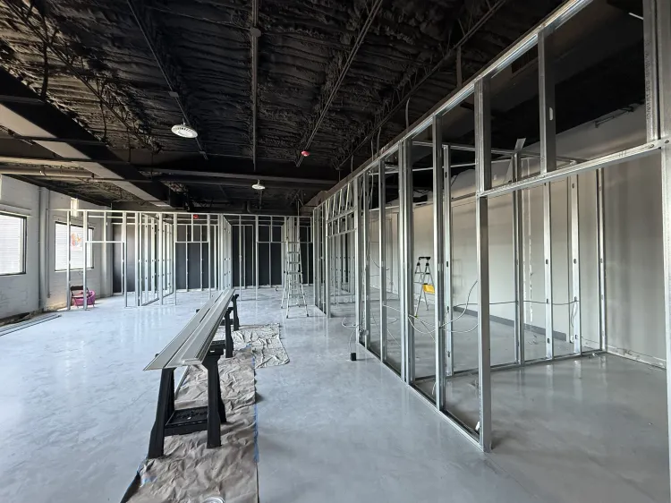 Interior of a building under construction with exposed metal framing and unfinished ceiling and floor