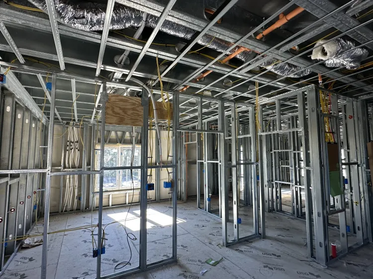 Interior of a house under construction with exposed metal framing, wiring, and unfinished walls.