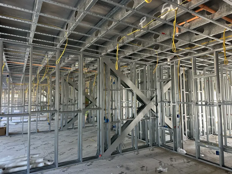Unfinished building interior with metal wall studs, ceiling framing, and construction debris on the floor