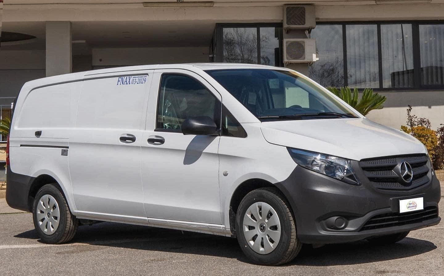 Un furgone bianco è parcheggiato davanti a un edificio.