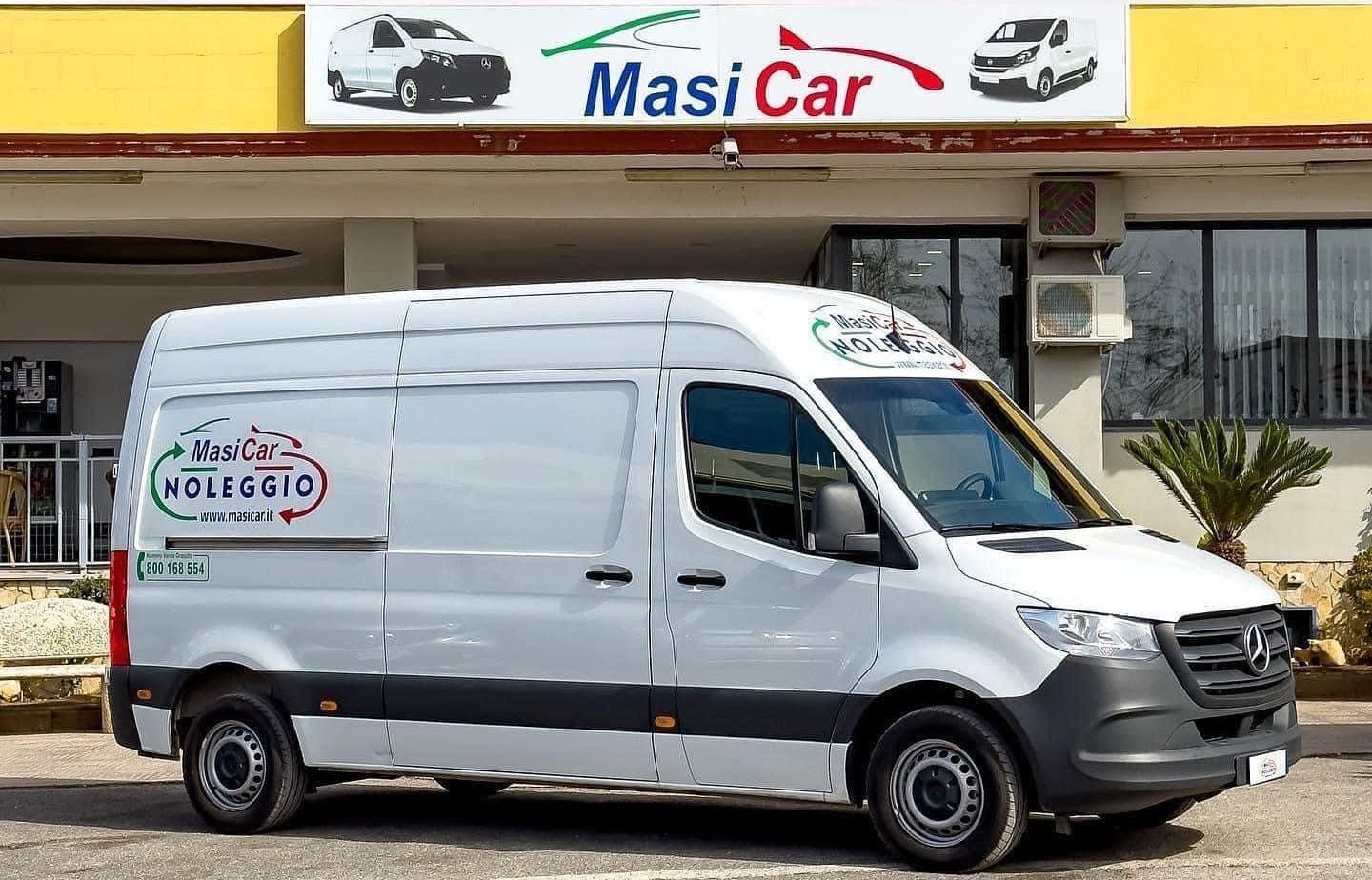 Un furgone bianco è parcheggiato davanti a un negozio di auto masi.