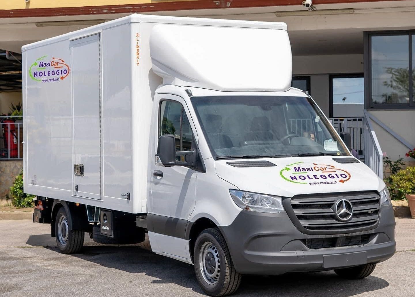 Un furgone Mercedes bianco è parcheggiato davanti a un edificio.