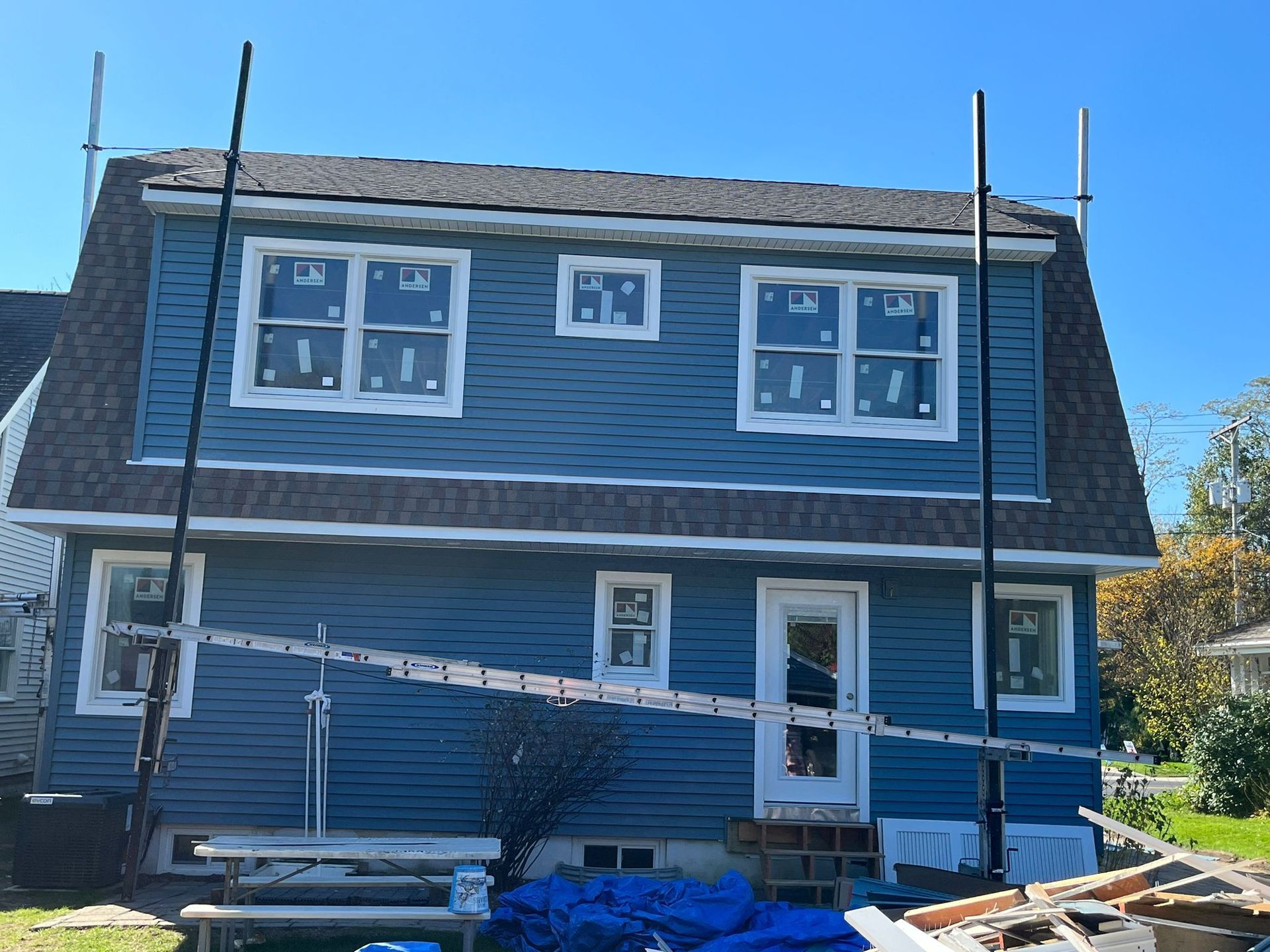 Blue house under renovation with scaffolding. New windows and siding are visible.