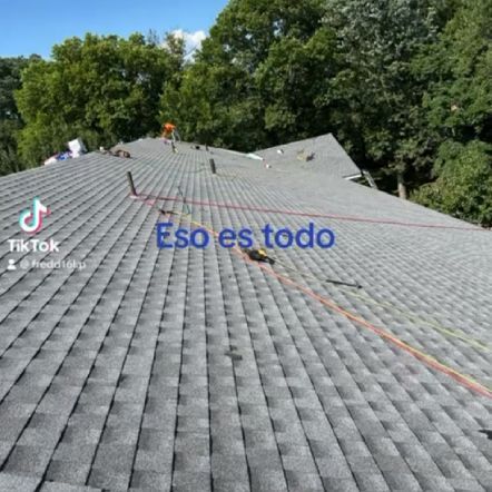 Workers on a newly shingled roof; gray asphalt shingles, trees in background, text 