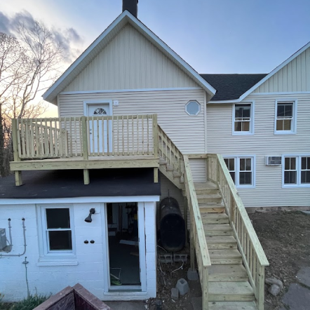 Two-story house with a deck and exterior staircase, and a shed with an open doorway.