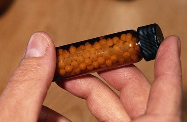 Una persona sostiene un pequeño frasco de pastillas en la mano.