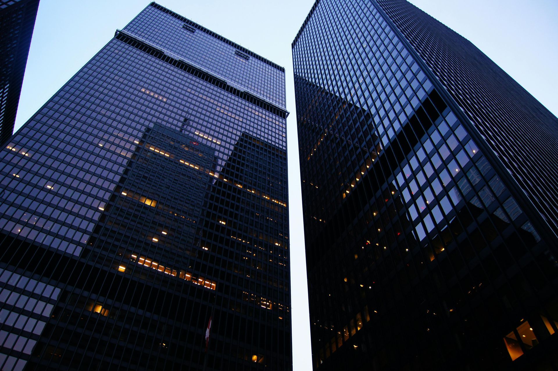 Looking up at two tall buildings with a blue sky in the background
