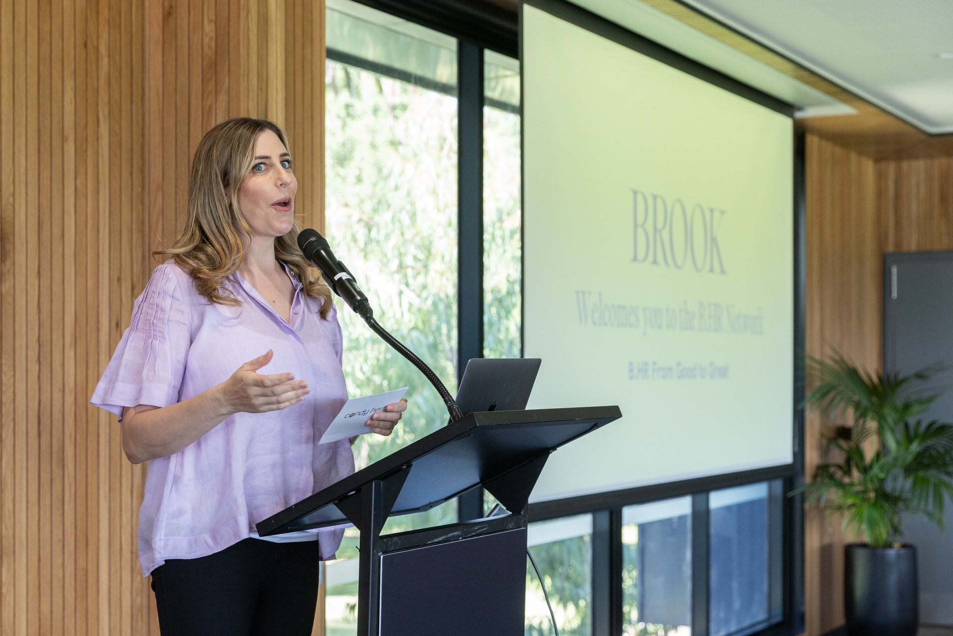Woman in purple top MCing event 
