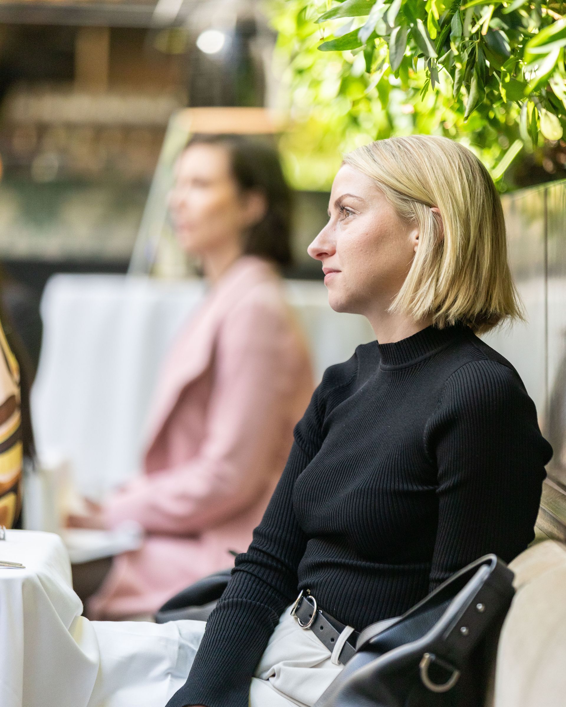 A woman in a black sweater is sitting in a chair.