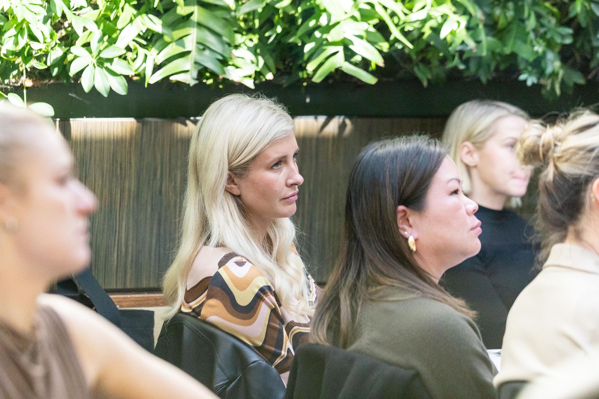 A group of women are sitting in a room looking at something.