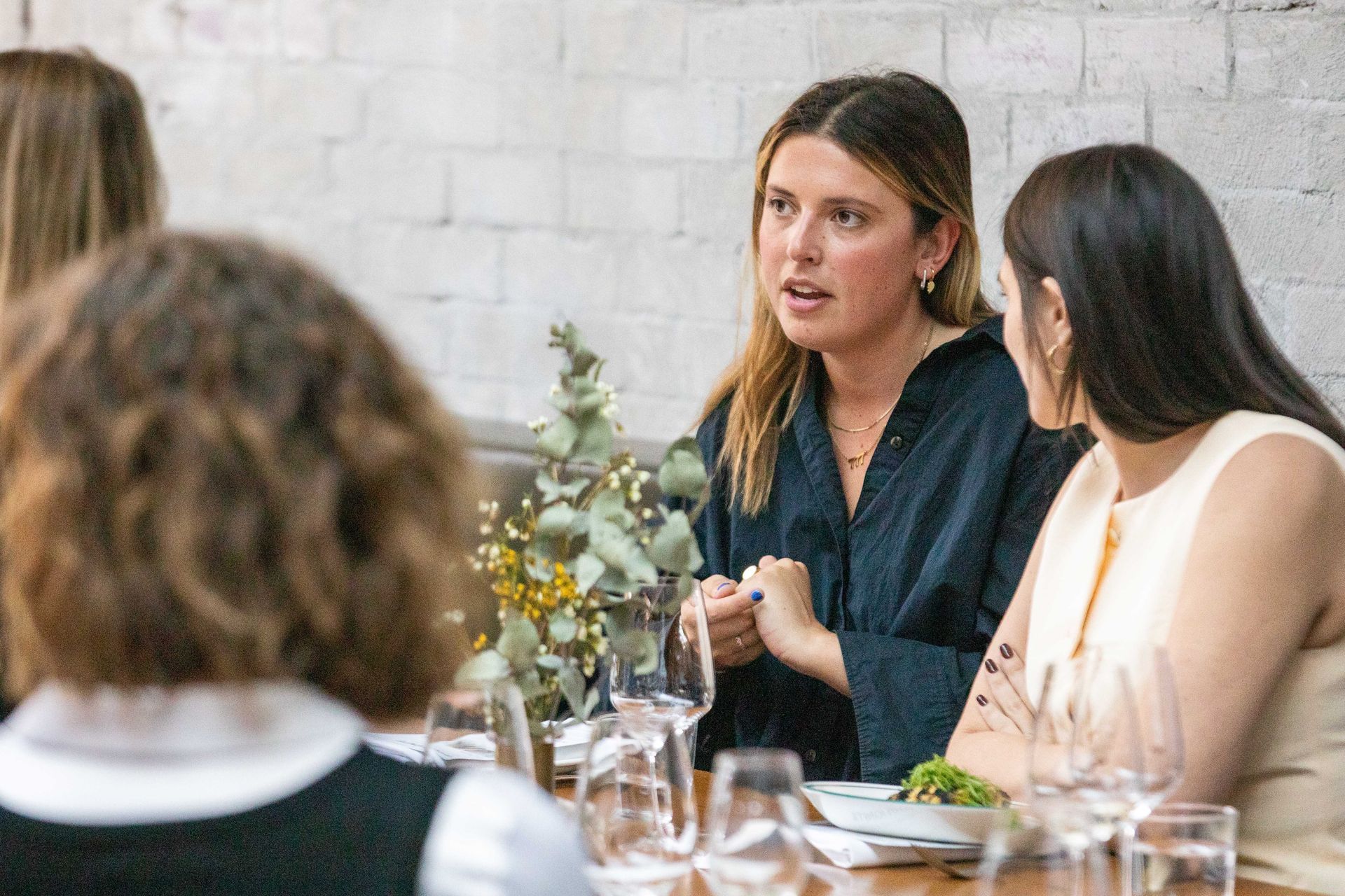 A group of women are sitting at a table talking to each other.