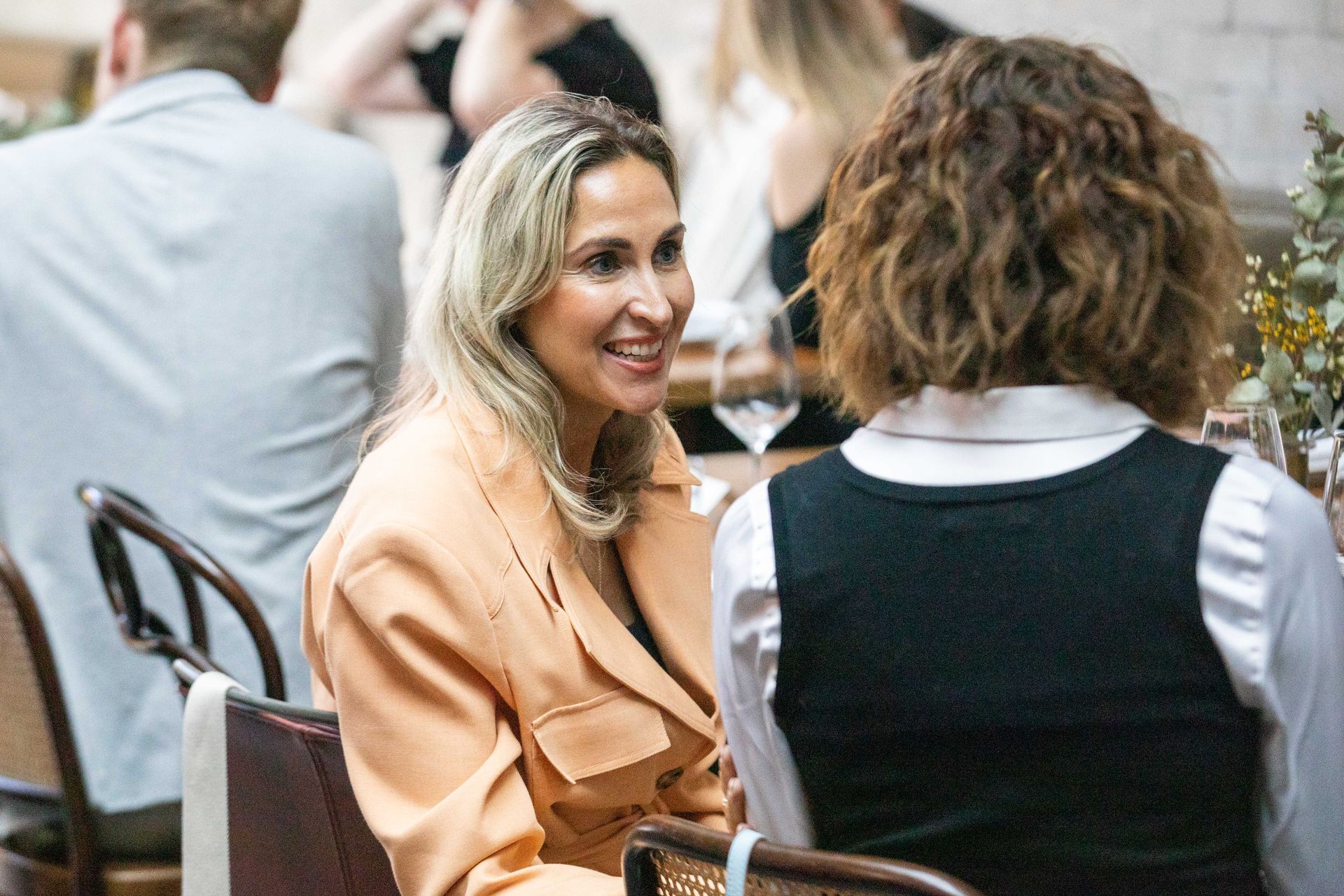 A woman is sitting at a table talking to another woman.