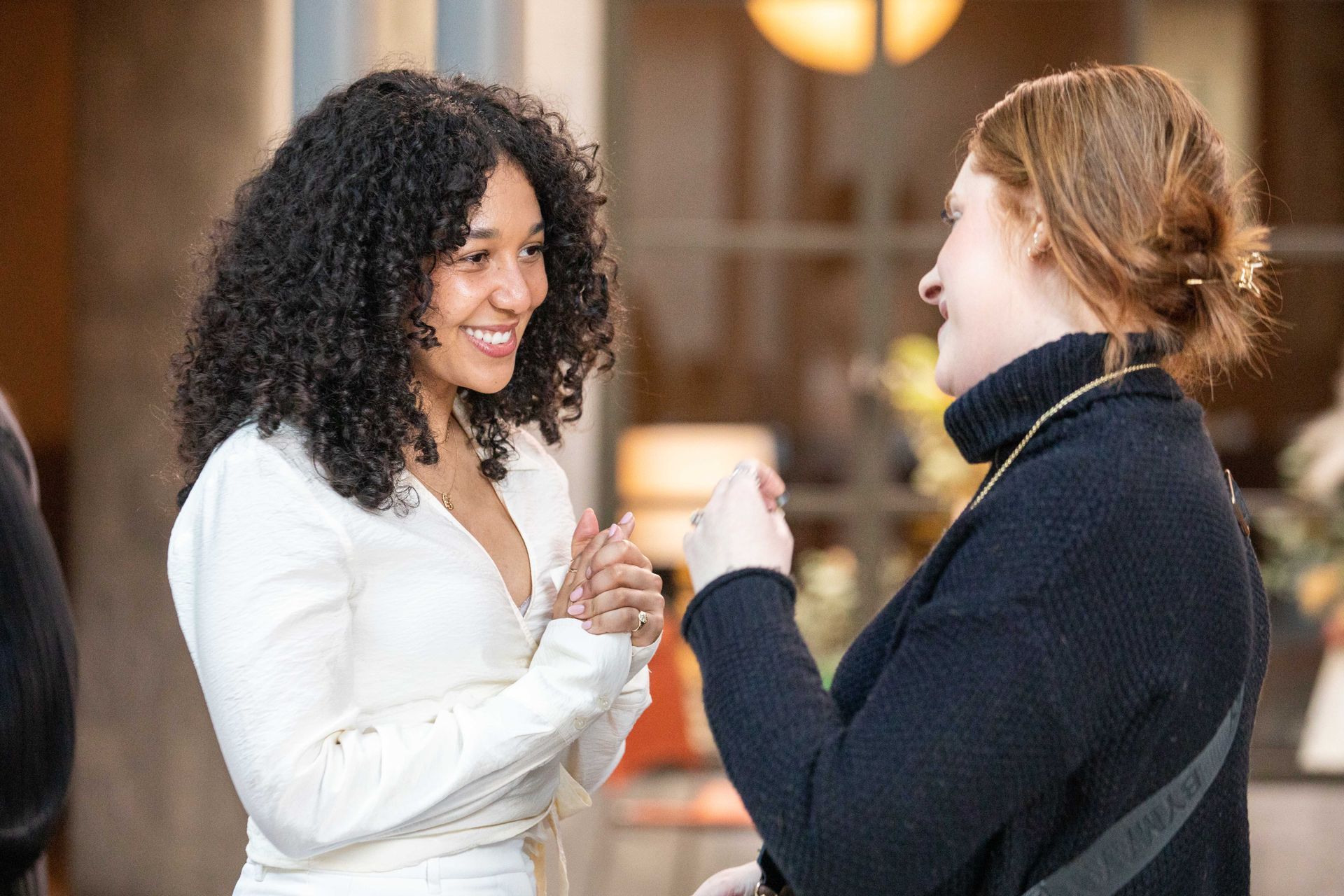 Two women are standing next to each other and talking to each other.