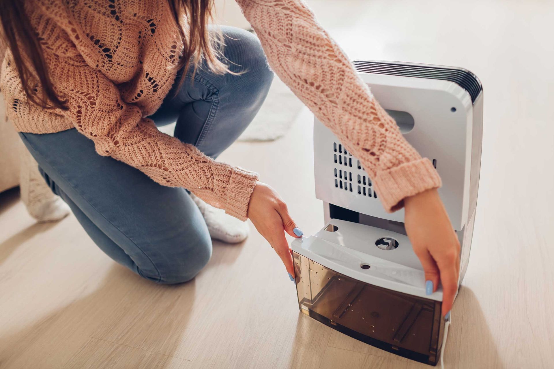 Person removing the water tank from a home dehumidifier.