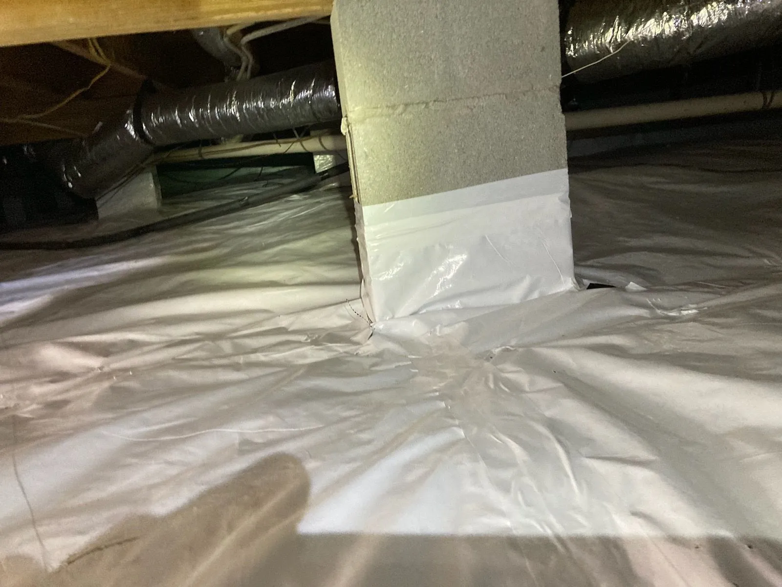 Sealed crawlspace with plastic vapor barrier covering the floor and support column.