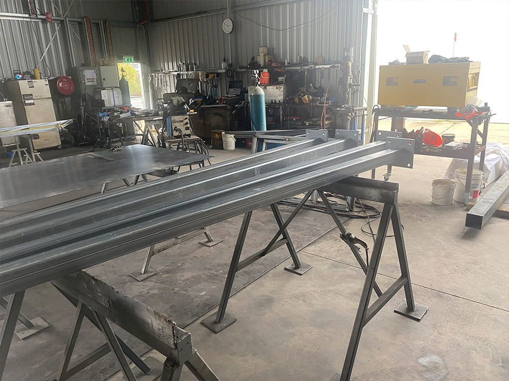 A Bunch Of Metal Pipes Are Sitting On A Table In A Factory — Quality Fabrications & Welding Pty Ltd In Bohle, QLD