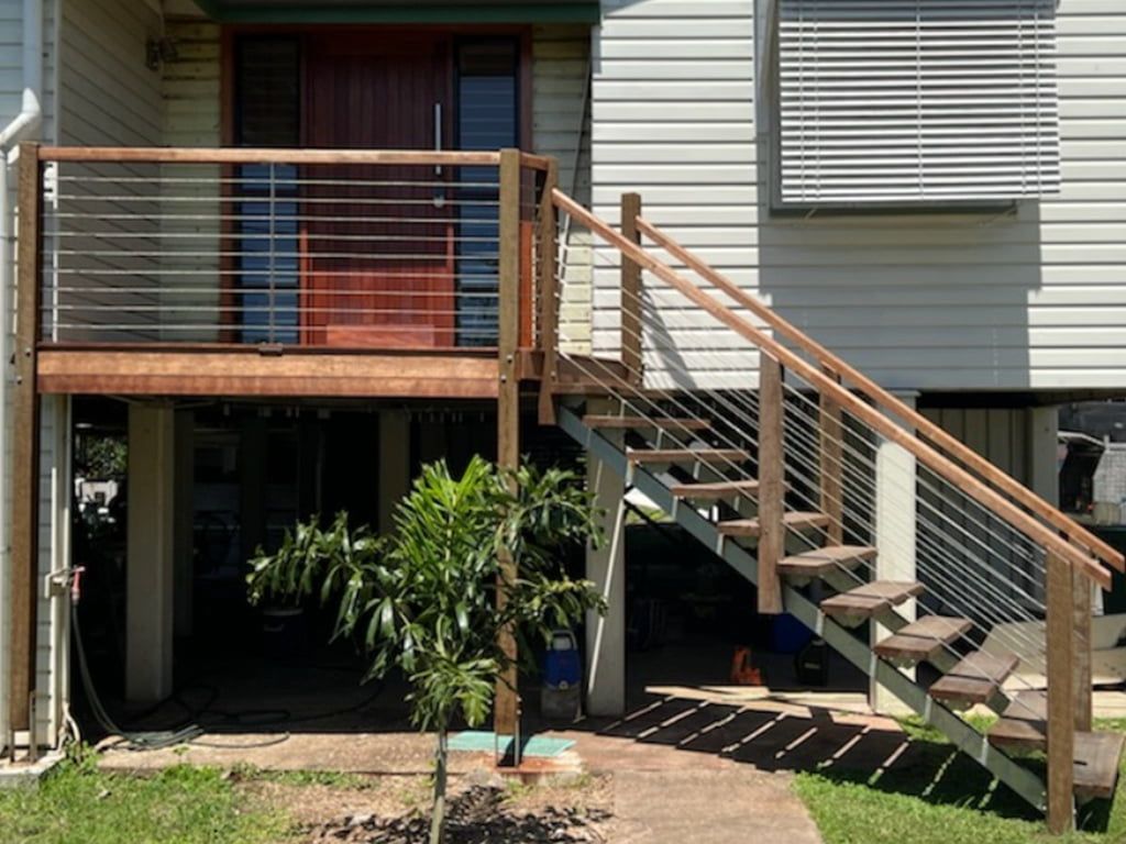 A House With A Wooden Deck And Stairs Leading Up To It — Quality Fabrications & Welding Pty Ltd In Bohle, QLD