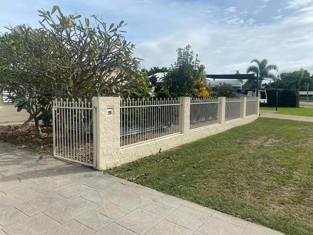 A White Fence Surrounds A Lush Green Yard In Front Of A House — Quality Fabrications & Welding Pty Ltd In Bohle, QLD