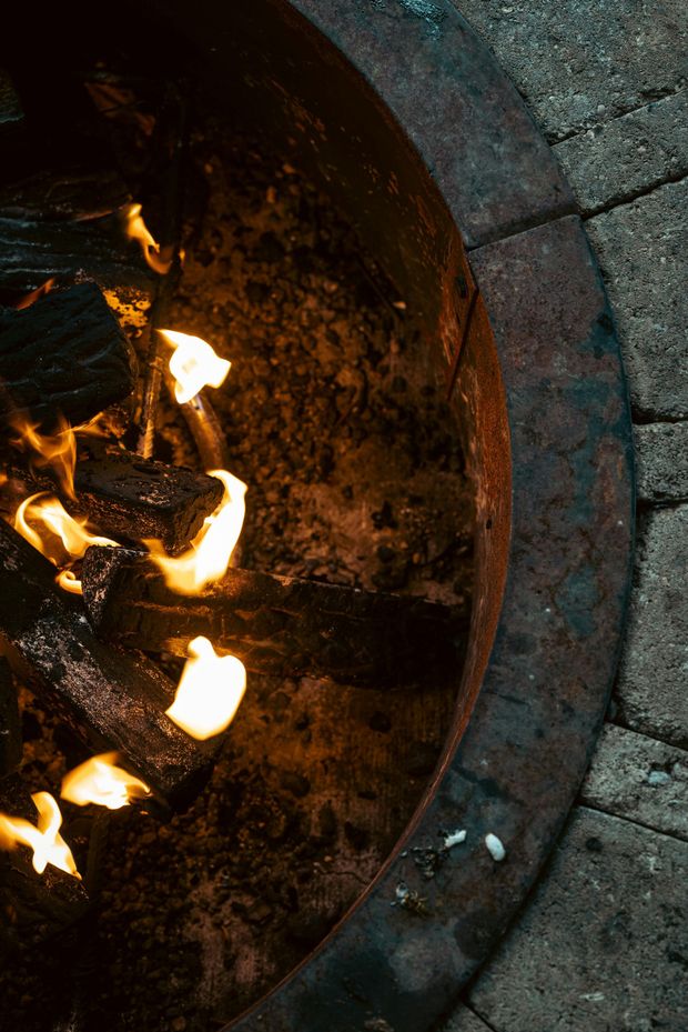 A close up of a fire pit filled with logs and flames.