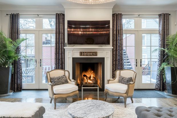 A living room with a fireplace , chairs , a table and a flat screen tv.