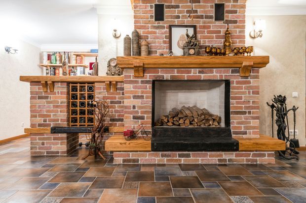 A brick fireplace with a wooden mantle in a living room.
