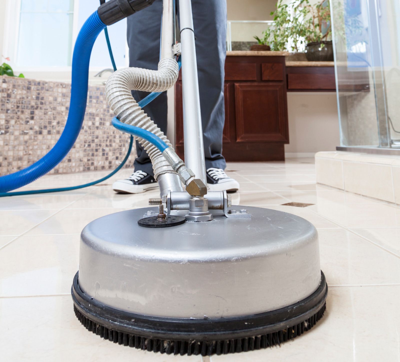 A person is cleaning a tile floor with a vacuum cleaner.