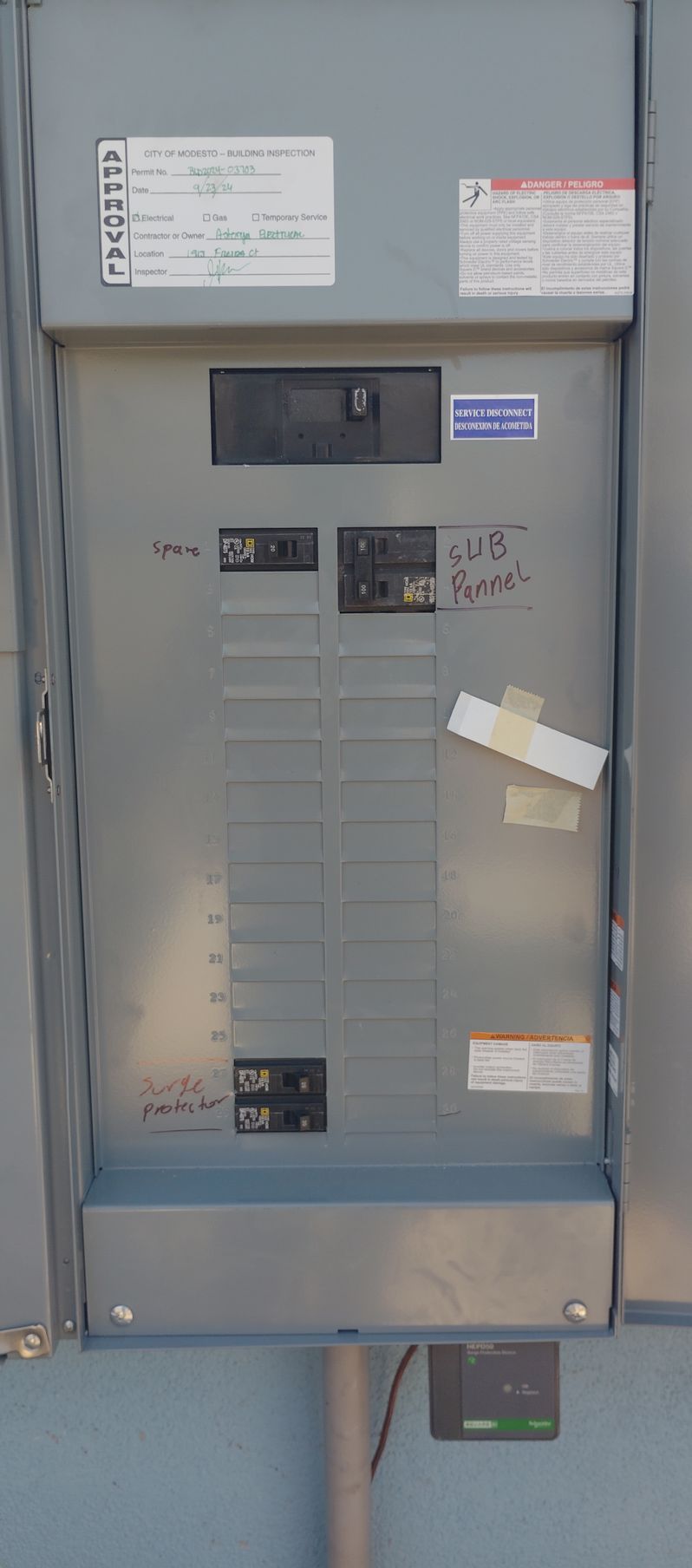 A electrical box is hanging on a wall next to a pipe.