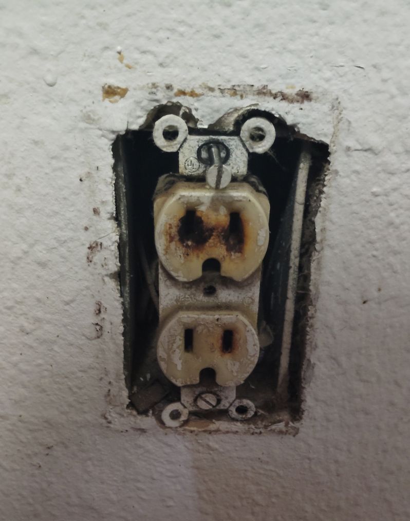 Two red electrical boxes with wires coming out of them on a white wall.