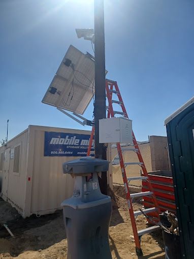 A ladder is sitting on top of a pole with a solar panel attached to it.