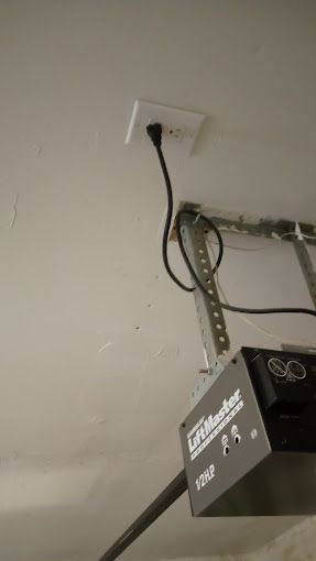 A garage door opener is hanging from the ceiling in a garage.