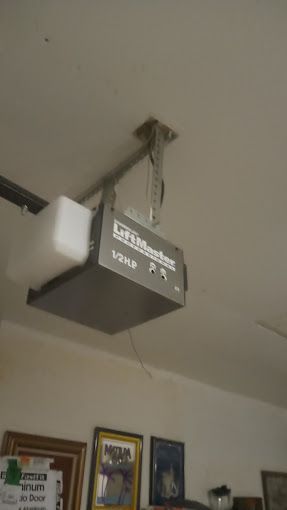 A garage door opener is hanging from the ceiling in a room.