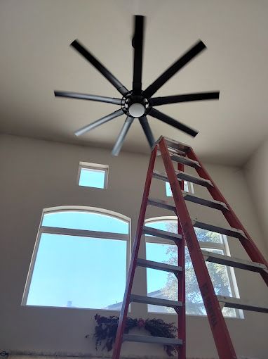 A ceiling fan is hanging from the ceiling above a ladder.