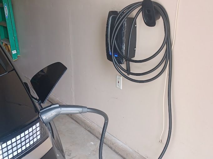 A car is being charged at a charging station in a garage.