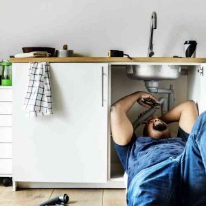 Man working under kitchen sink.
