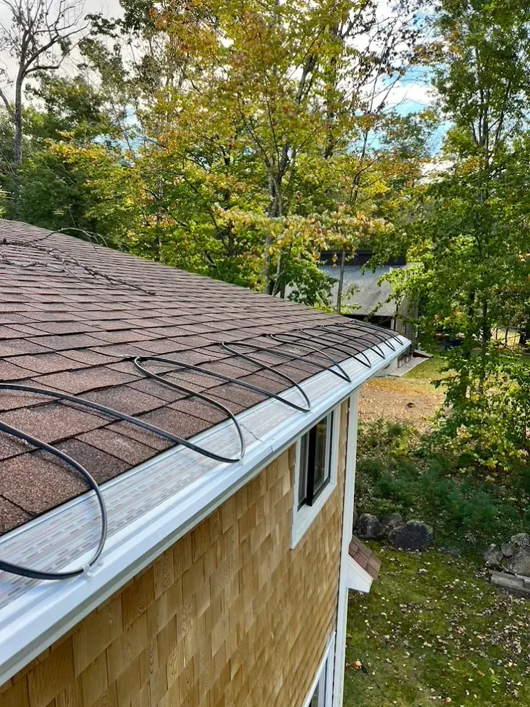 A house with a gutter on the roof and trees in the background.