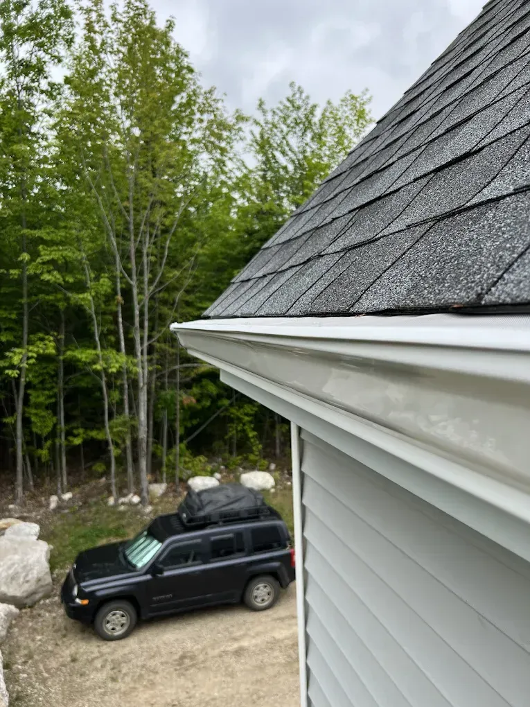 A black suv is parked on the side of a house next to a gutter.