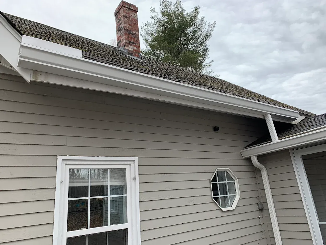 A house with a chimney on the roof and a window on the side.