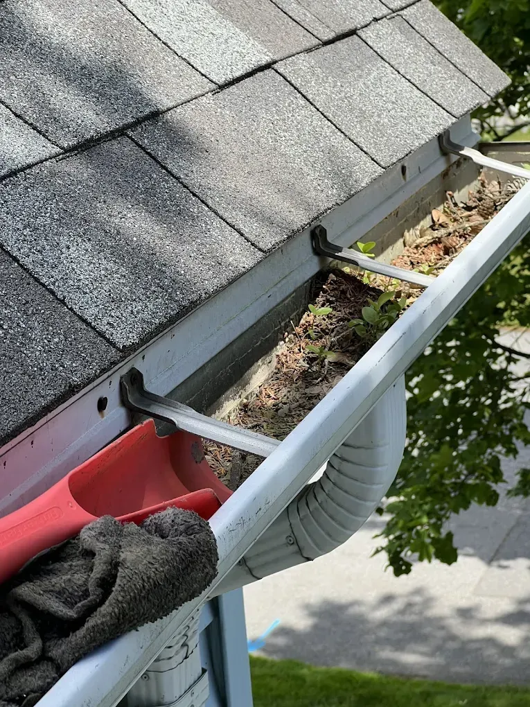 A person is cleaning a gutter on the roof of a house.