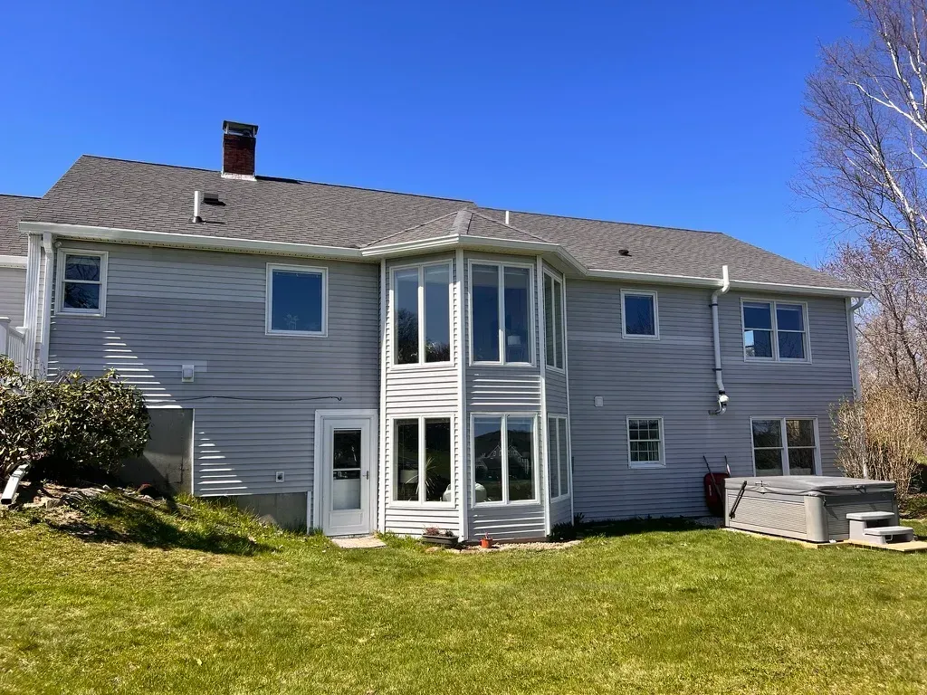 A large house with a lot of windows and a hot tub in the backyard